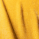 Gros plan sur un tissu jaune dont la texture est visible et dont les ombres créent des lignes diagonales sur la surface. Canape Paris by Atelier Bis