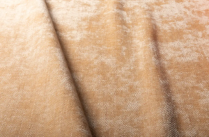 Gros plan sur un tissu de velours beige doux, à la brillance subtile et aux plis délicats en diagonale. Canape Paris by Atelier Bis