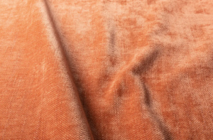 Gros plan sur un tissu orange souple et texturé, aux plis subtils et à la surface légèrement brillante. Canape Paris by Atelier Bis