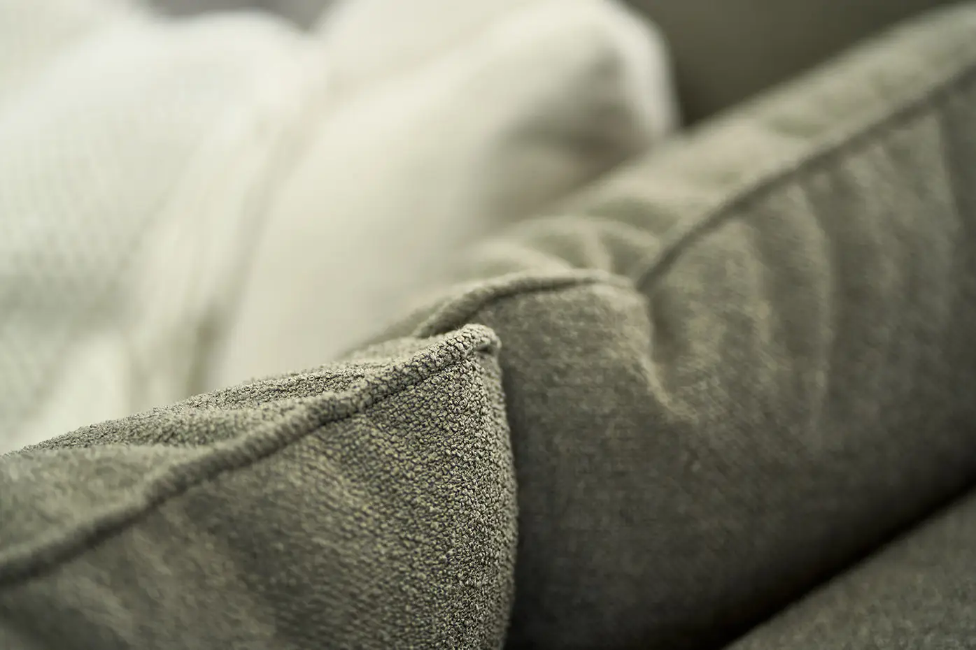 Gros plan d'un coussin de canapé gris texturé avec une couverture de couleur crème en arrière-plan. Canape Paris by Atelier Bis