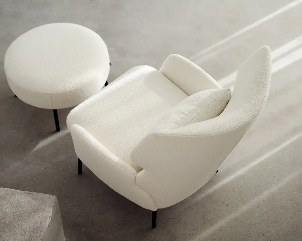 Un fauteuil blanc rembourré et un ottoman rond assorti sur un sol gris clair, vus de dessus. Canape Paris by Atelier Bis