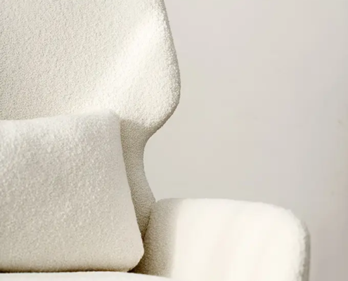 Gros plan sur un fauteuil moderne blanc texturé avec un coussin rectangulaire assorti. Canape Paris by Atelier Bis