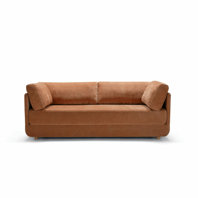 Un canapé rembourré marron avec deux coussins cylindriques assortis, sur fond blanc. Canape Paris by Atelier Bis