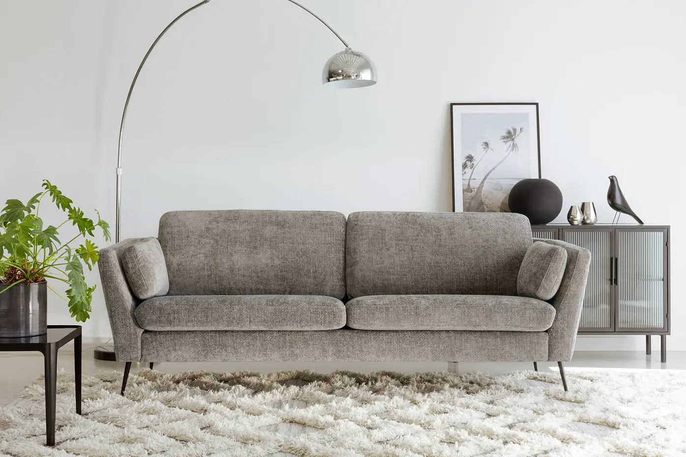 Salon moderne avec un canapé gris, un lampadaire en arc, un buffet, une décoration et un tapis blanc à poils longs. Canape Paris by Atelier Bis